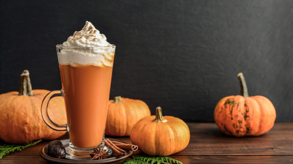 Pumkin Spice Latte, Kürbisse und ein Glas Pumpkin Spice Latte auf einem Tisch